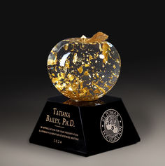 an apple shaped award on top of a black base with gold flecks in it