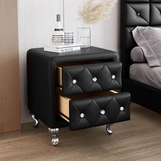 a black leather nightstand with two drawers on each side and a white bed in the background