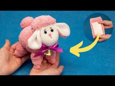 a hand holding a pink stuffed animal with a bell