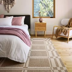 a bedroom with a bed, two chairs and a rug in front of the window