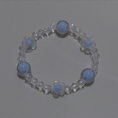 a beaded bracelet with blue beads and clear glass balls is shown on a gray surface