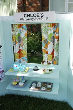 a table with cupcakes and cakes on it in front of a window that says chloe's bakery & cafe