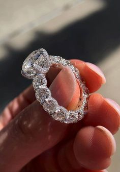 a person holding a diamond ring in their hand, with the middle part of it surrounded by smaller diamonds