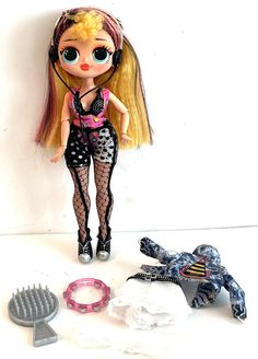 a doll with headphones standing next to a hair dryer and other toys on a white surface