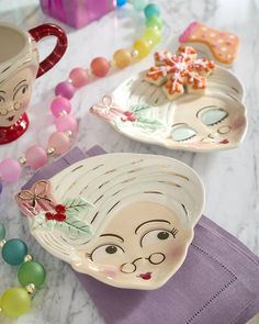 two plates with faces on them sitting on a table next to bead necklaces