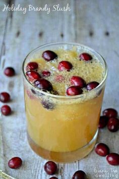 a glass with some fruit in it on top of a table next to cranberries