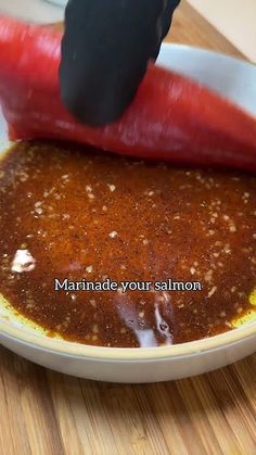 someone is cutting up some food in a bowl on a wooden table with the words marinade your salmon above it