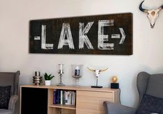 a wooden sign that says lake hanging on the wall in a living room with two chairs