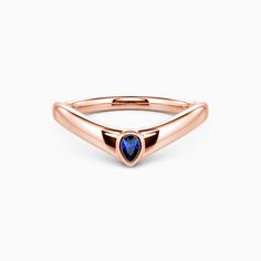 a rose gold ring with a blue stone in the middle and an arrow shaped band