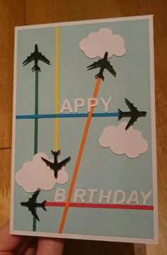 someone is holding up a birthday card with airplanes flying in the sky and clouds on it