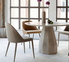 a round table with chairs around it and flowers in vase on the table next to it