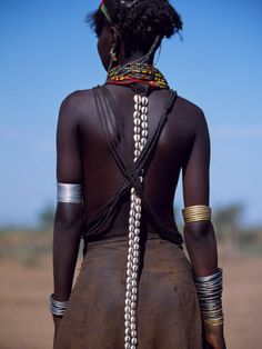 the back of a woman wearing beaded necklaces and headdress in africa