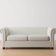 a couch sitting on top of a hard wood floor next to a white painted wall