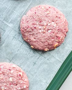 two pink cookies sitting on top of a piece of paper