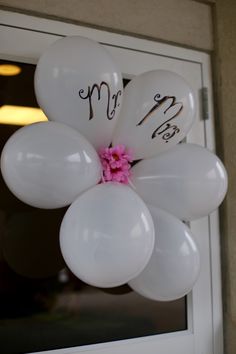 white balloons with pink flower and mr and mrs written on them hanging from the front door