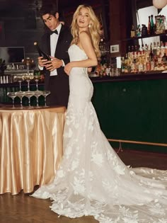 a man and woman standing next to each other in front of a table with drinks