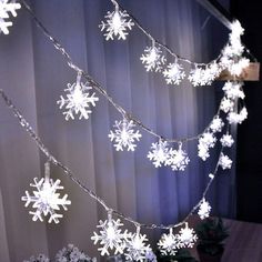 snowflake lights are hanging from a curtain