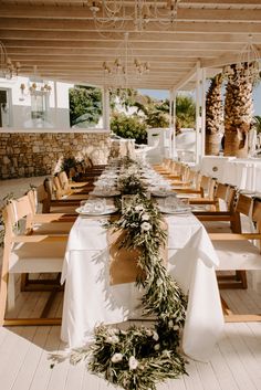 an outdoor dining area with white tablecloths and wooden chairs set up for a meal