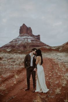 a bride and groom kissing in front of the red rock formations at monument national park