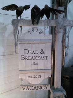 three black birds perched on top of a dead and breakfast sign