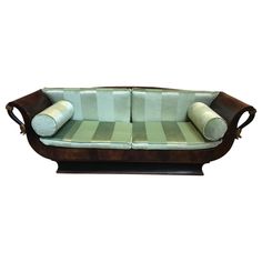 a wooden couch with two pillows on it's back and arm rests in front of a white background