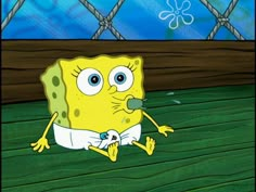 spongebob sitting on the ground in front of a fence