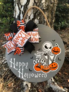 a wooden sign that says happy halloween hanging on a tree