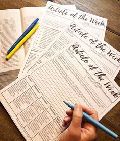 a person is writing on some paper with pencils and a book in the background