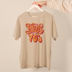 "\"Take Me Back to the 70s\" T-shirt! This shirt is perfect for anyone who longs for the era of groovy tunes, flower power, and disco fever. Whether you're a true child of the 70s or just love the fashion and culture of the era, this T-shirt is a must-have addition to your wardrobe. Pair it with your favorite jeans, flares, or corduroys, and you'll be ready to dance the night away at any disco-themed party or concert. So don't wait - grab your \"Take Me Back to the 70s\" T-shirt today and let your inner flower child shine!" 60s T Shirt Design, 70s Inspired Cotton Tops With Retro Print, 1970s Retro Print Cotton Top, 1970s Cotton Tops With Retro Print, Cotton Tops With Retro 70s Print, Wifey Shirt, 70s T Shirts, Groovy Shirt, Stay Groovy