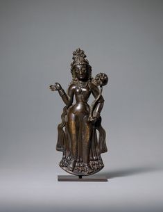 a bronze statue sitting on top of a wooden stand