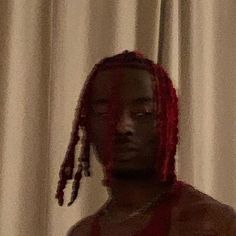 a woman with red dreadlocks standing in front of a curtain