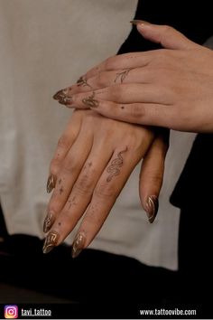 two hands with gold nail polish holding each other