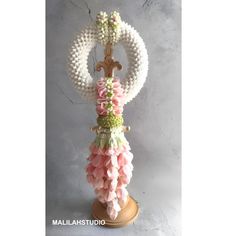 a cross made out of beads and flowers on top of a wooden stand in front of a gray wall