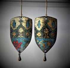 two earrings hanging from hooks with designs on them