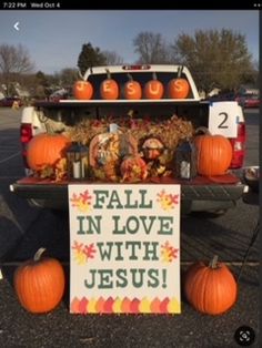 a truck with pumpkins and decorations on it's bed in a parking lot next to a sign that says fall in love with jesus