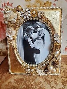 an ornate gold frame with pearls and flowers on the edges, holds a wedding photo