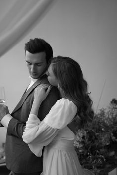 a man and woman standing next to each other while holding wine glasses in their hands