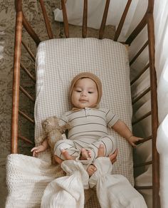 a baby laying in a crib next to a stuffed animal