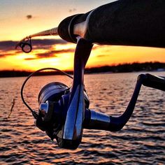 a fishing rod is attached to the handle of a boat at sunset or dawn over water