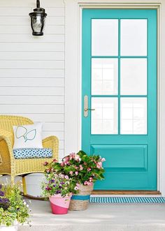 the front door is painted bright blue and has potted plants on the porch outside