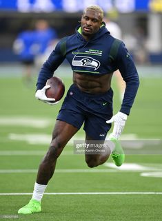 a man running with a football in his hand and wearing green shoes on the field