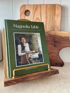 a wooden cutting board sitting on top of a counter next to a green book cover