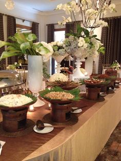 the buffet table is set up with flowers and desserts