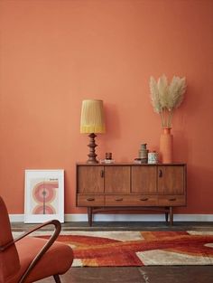 a living room with an orange wall and wooden furniture in front of a painting on the wall