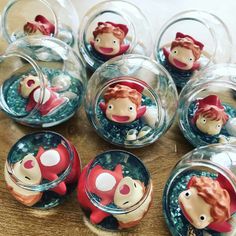 several glass containers filled with little figurines sitting on top of a wooden table