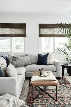 a living room filled with furniture and pillows on top of a rug next to a window