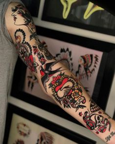 a man's arm with tattoos on it in front of some framed pictures and other artwork