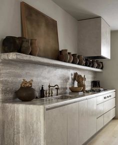 a kitchen with white cabinets and shelves filled with vases on top of the counter