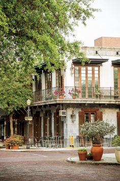 an old building with balconies and potted plants on the sidewalk in front