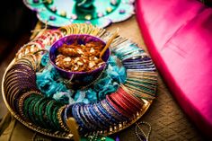 colorful plates and bowls filled with food sit on a table next to a pink pillow